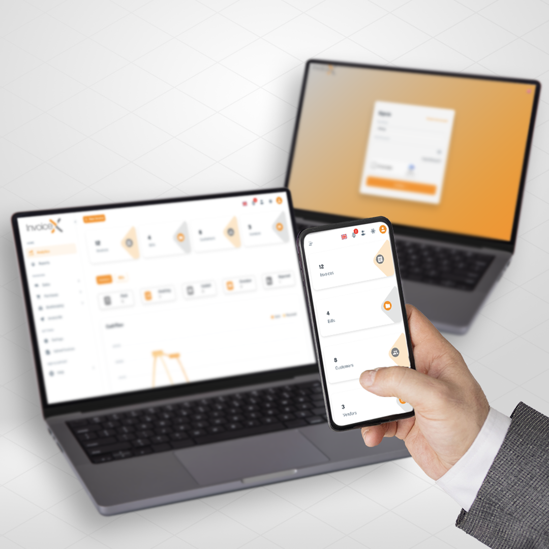 Person holding phone showing financial app screen with laptop displaying financial data in the background on a desk